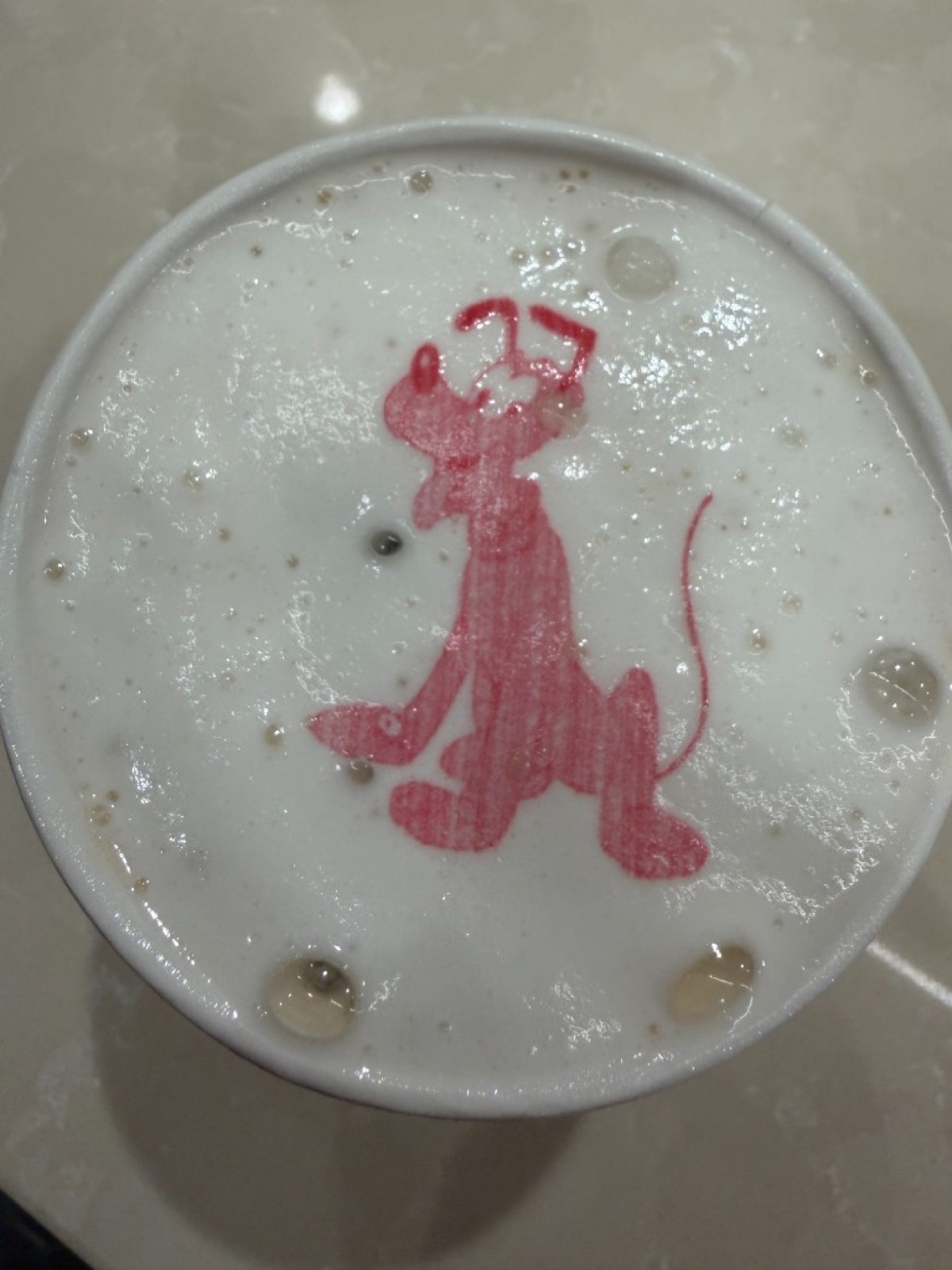 Specialty latte with Pluto character art on the foam from a Disney Cruise Line café